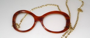 Eine echte 70er  Jahre Azetat Brillenfassung für den ausgefallenen Geschmack ! Die Goldkette mit dem Amulett wird hinter die Ohren gehängt und hält die Brille durch das Gewicht des Schmuck Amulettes