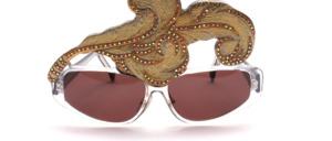 A crystal color sunglasses with a large golden leaf, which is set with many golden, glittering rhinestones